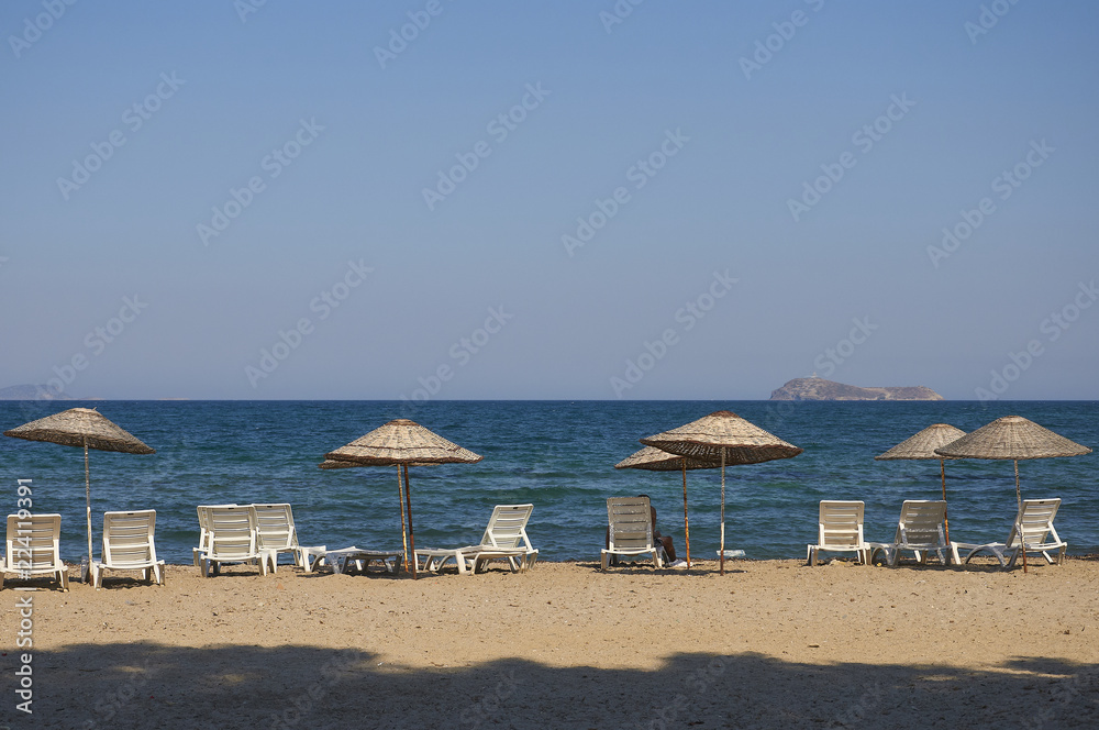Beach with sun umbrellas and loungers. The coast resorts of the Aegean Sea of Turkey. Turgutreis , Bodrum.