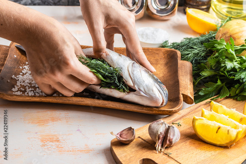 Process of cooking Dorado fish with lemon, olive oil and herbs. Female hands close-up. Concept of homemade food, culinary hobby