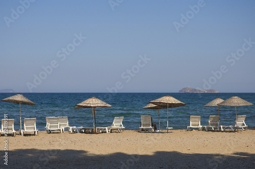 Beach with sun umbrellas and loungers. The coast resorts of the Aegean Sea of Turkey. Turgutreis   Bodrum.
