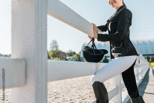 cropped image of smiling equestrian leaning on fence at horse club photo