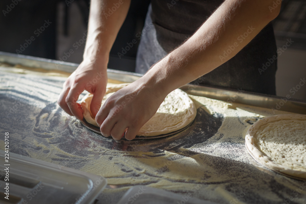 Baker forms a round base for pizza making Baker forms a round base for pizza making