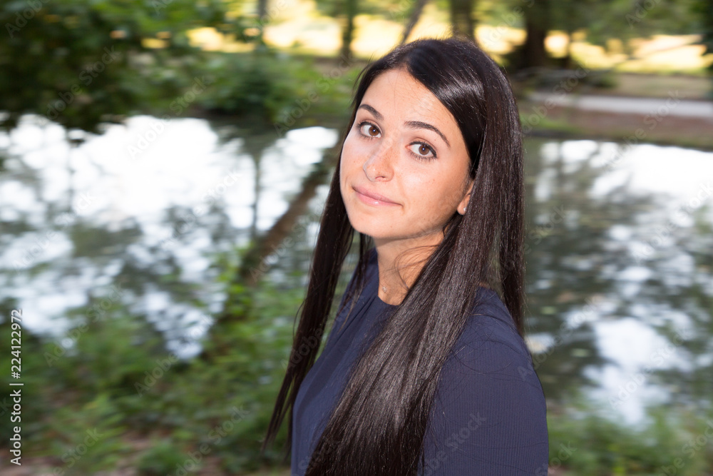 Happy woman with lovely smile standing on river lake park promenade in summer looking at the camera with a joyful expression Happy woman with lovely smile standing on river lake park promenade in summer looking at the camera with a joyful expression