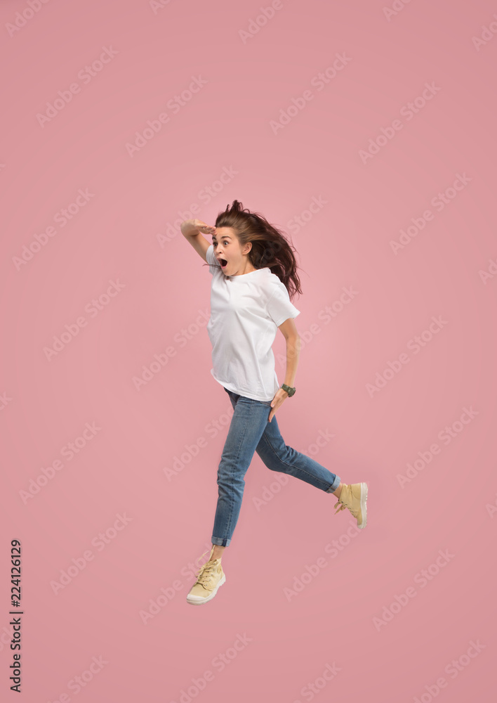 What is there interesting in the distance. seeking pretty happy young woman jumping and gesturing against pink studio background. Runnin girl in motion or movement. Human emotions and facial