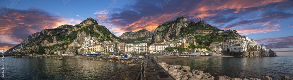 Beautiful panorama of Amalfi, the main town of the coast on which it is located taken from the sea. Situated in province of Salerno, in the region of Campania, Italy, on the Gulf of Salerno at sunset - obrazy, fototapety, plakaty 