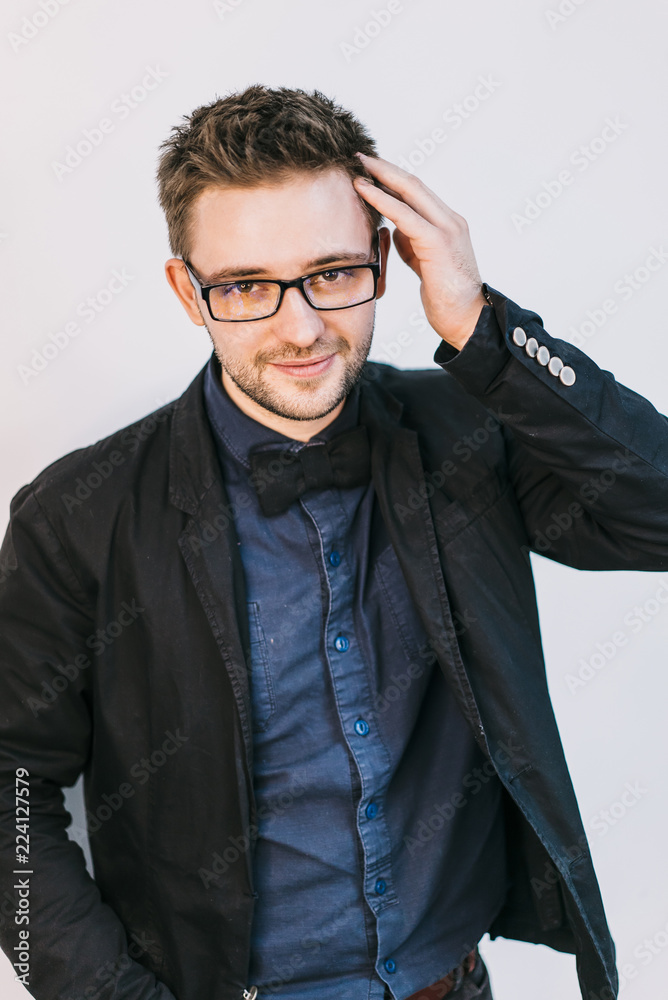 a young man with glasses with a stylish hairstyle touches hair by hand on a white background a young man with glasses with a stylish hairstyle touches hair by hand on a white background