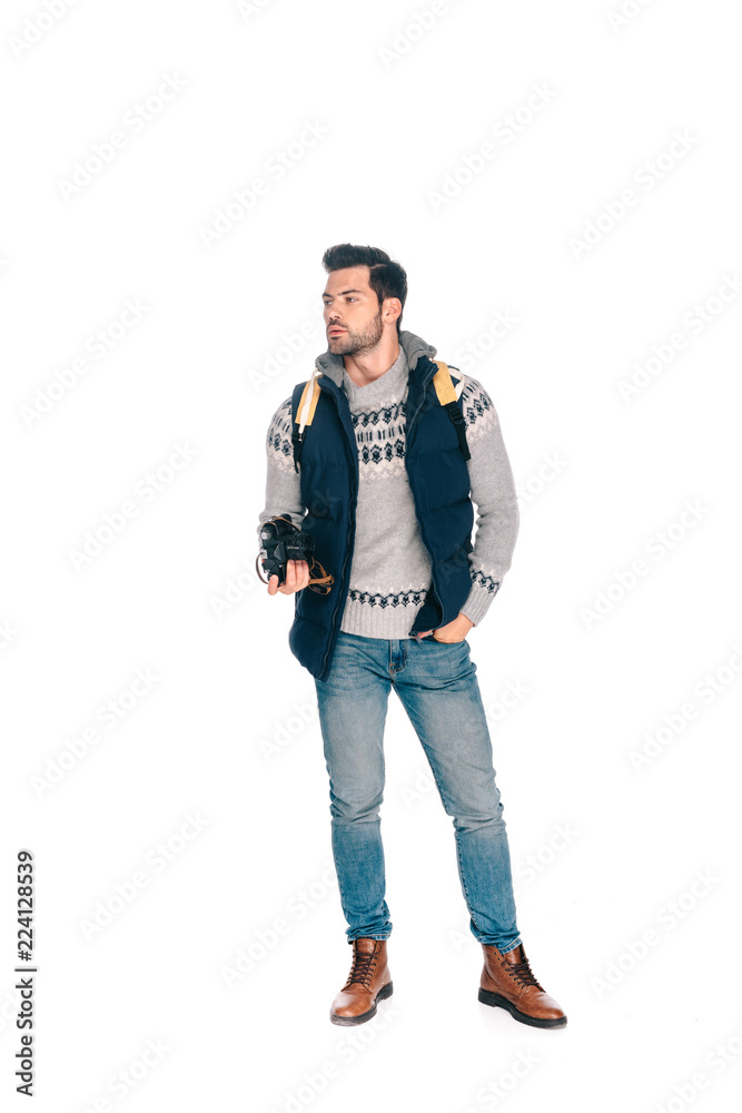 full length view of young man with backpack holding camera and looking away isolated on white full length view of young man with backpack holding camera and looking away isolated on white