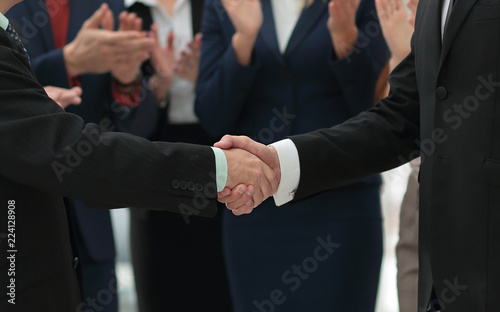 closeup of handshake of business partners on background of employees