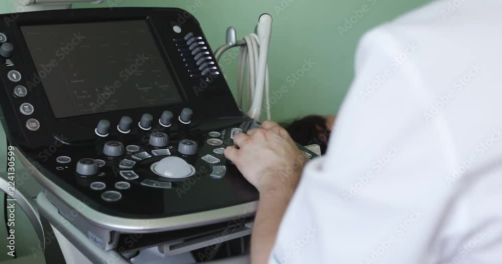 Doctor works on the ultrasound machine clicks on the buttons.