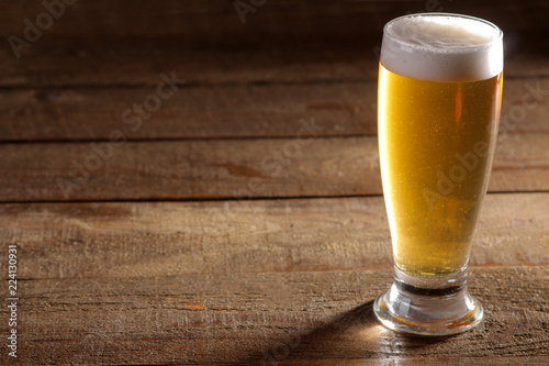 A glass of light beer on a wooden brown background with a place for an inscription