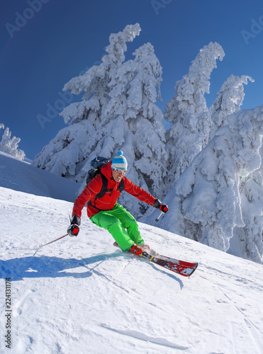 Skier skiing downhill in high mountains against blue sky
