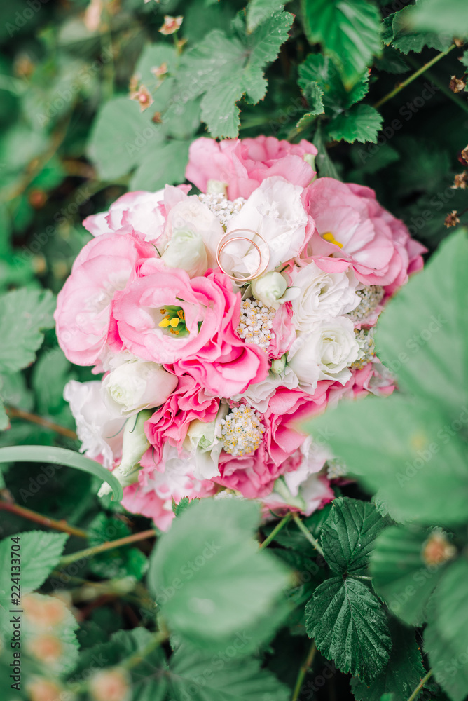 Fototapeta premium Wedding rings on white pink weddding bouquet.