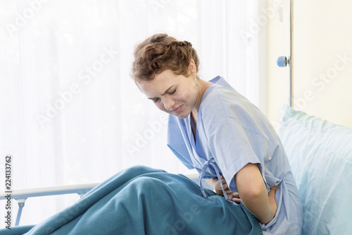 Beautiful young woman patient with period pain on hospital bed room.Copy space.