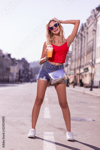 Pleasurable time. Beautiful young woman drinking orange juice while having a pleasant walk