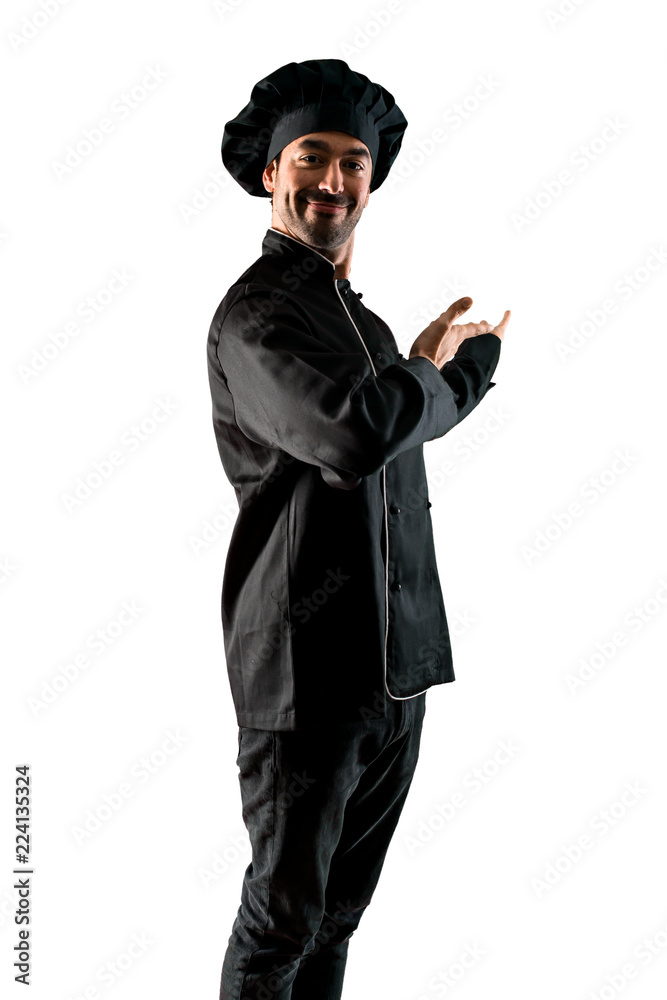 Chef man In black uniform presenting and inviting to come with hand on isolated white background Chef man In black uniform presenting and inviting to come with hand on isolated white background