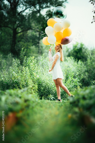 young girl with balloons on nature background