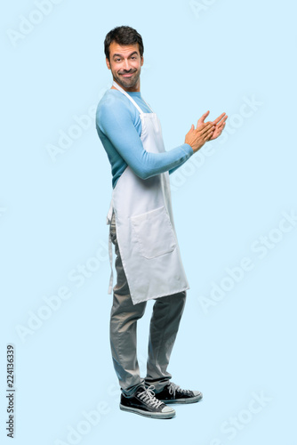 Full body of Man wearing an apron applauding after presentation in a conference on blue background