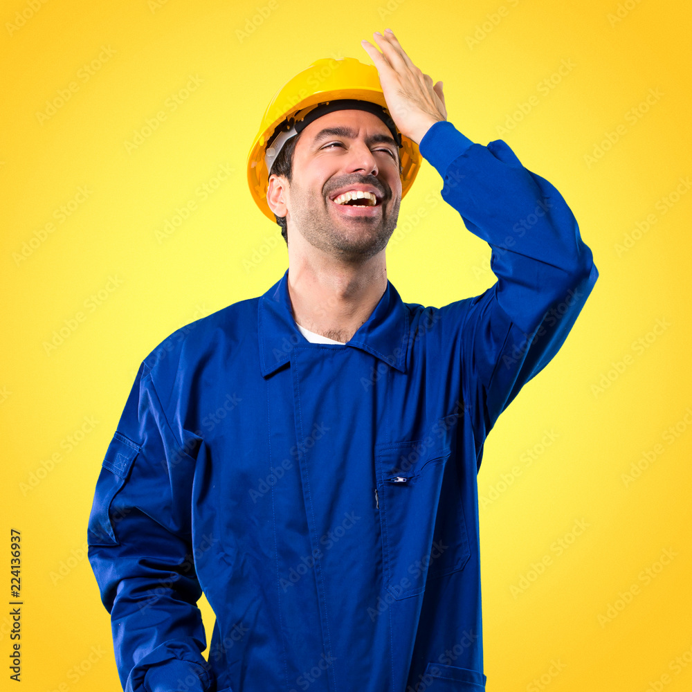 Young workman with helmet has just realized something and has intending the solution on yellow background