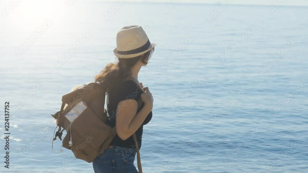 Woman traveler with dog in the backpack and looking at sea. Concept of travel. Woman traveler with dog in the backpack and looking at sea. Concept of travel.
