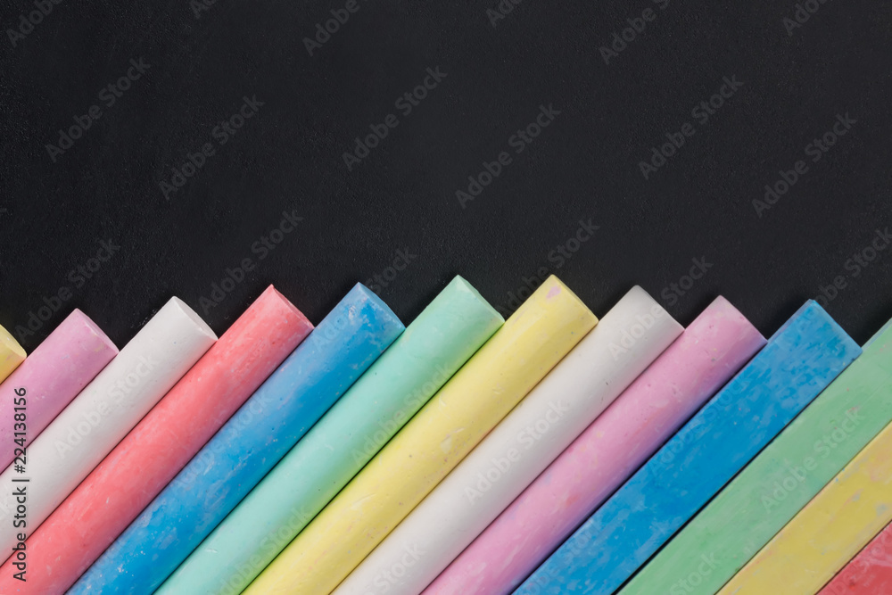 a set of colorful chalks, on a black educational board, there is a place for an inscription from above a set of colorful chalks, on a black educational board, there is a place for an inscription from above