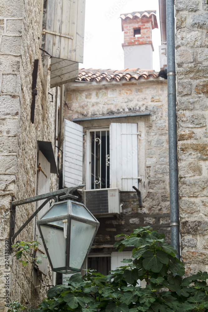 courtyard in Budva Old Town and stone wall with closed wooden shutters window
