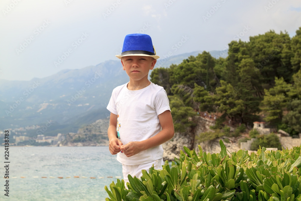 boy in blue hat walks on the beach in Milocher Park near Budva, Montenegro