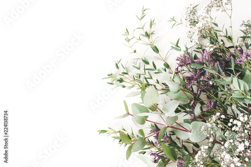 Fototapeta Naklejka Na Ścianę i Meble -  Wedding, birthday styled stock photo. Feminine scene, floral composition. Bunch of eucalyptus branches, baby's breath Gypsophila and limonium flowers. White table background. Flat lay, top view.