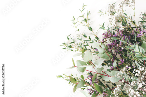 Wedding  birthday styled stock photo. Feminine scene  floral composition. Bunch of eucalyptus branches  baby s breath Gypsophila and limonium flowers. White table background. Flat lay  top view.