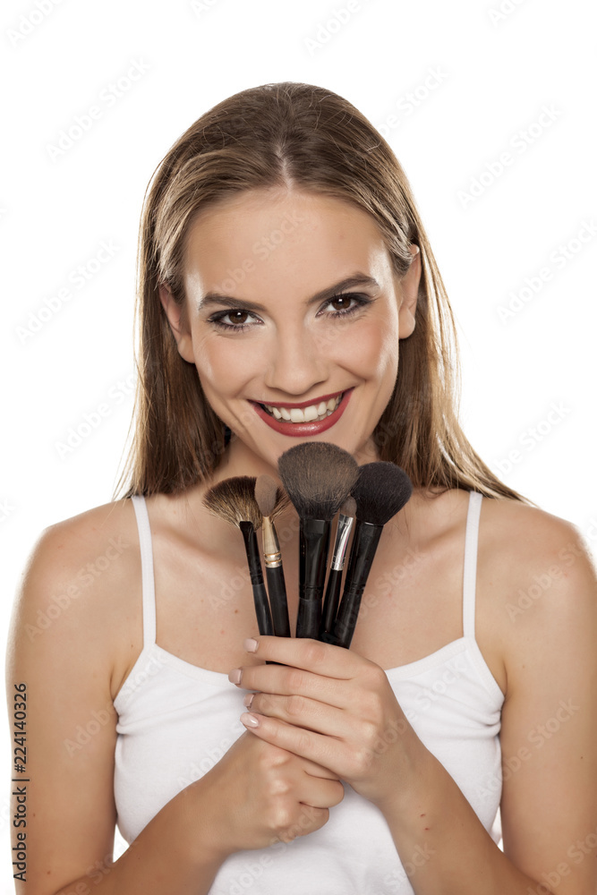 young beautiful girl posing with makeup brushes on white backgeound young beautiful girl posing with makeup brushes on white backgeound