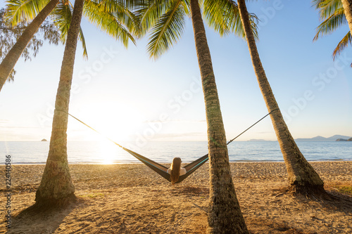 Fototapeta Naklejka Na Ścianę i Meble -  Woman on hammock amongst palm trees on a beach