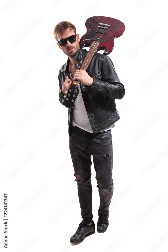 Naklejka premium fashion man with guitar on shoulder walking while holding collar