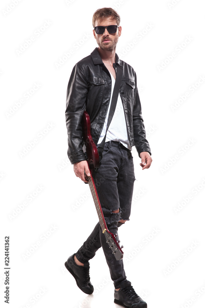 handsome fashion man stepping to side while holding guitar handsome fashion man stepping to side while holding guitar