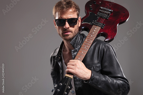 portrait of young blond man holding guitar on shoulder