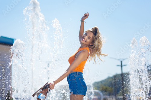 I am happy. Cheerful positive woman jumping in the fountain while expressing her wonderful mood