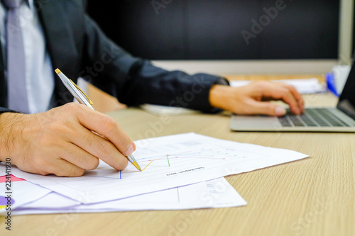 Businessman using red pen writing in notepad on office table