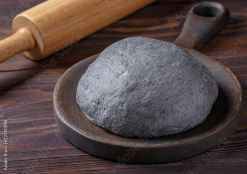 Black yeast dough on dark wooden table. Color dough for black Halloween pizza or bun.