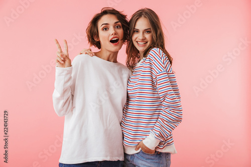 Women friends isolated over pink wall background posing.