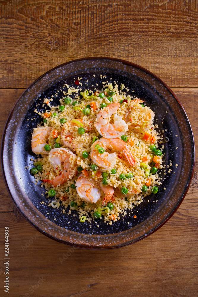 Shrimps with couscous, green peas, leeks and carrot. overhead, vertical