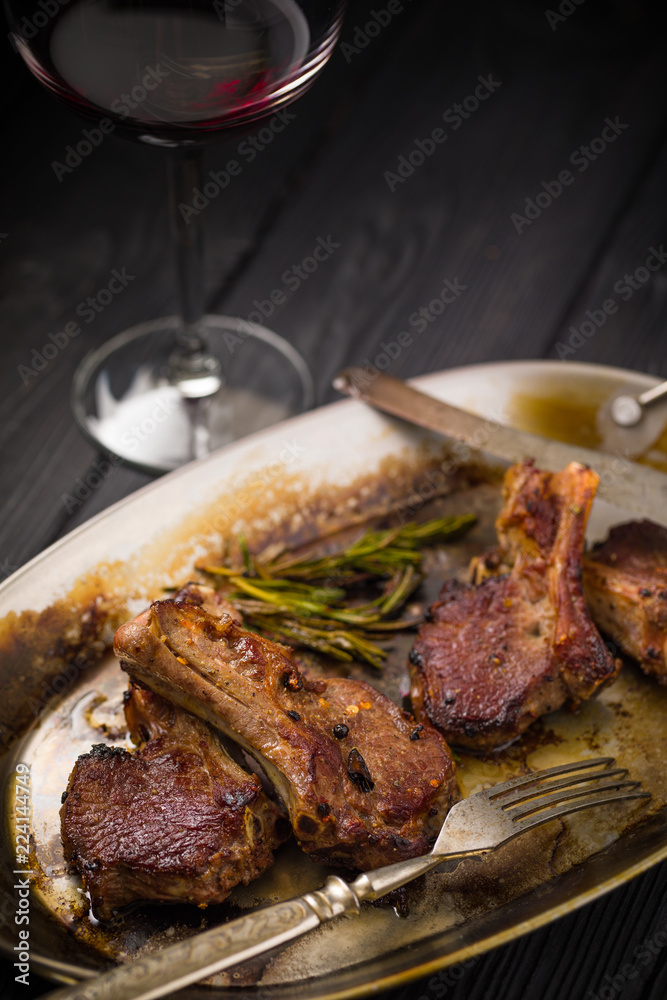 Lamb chops on a metal rustic plate with rosemary and spices