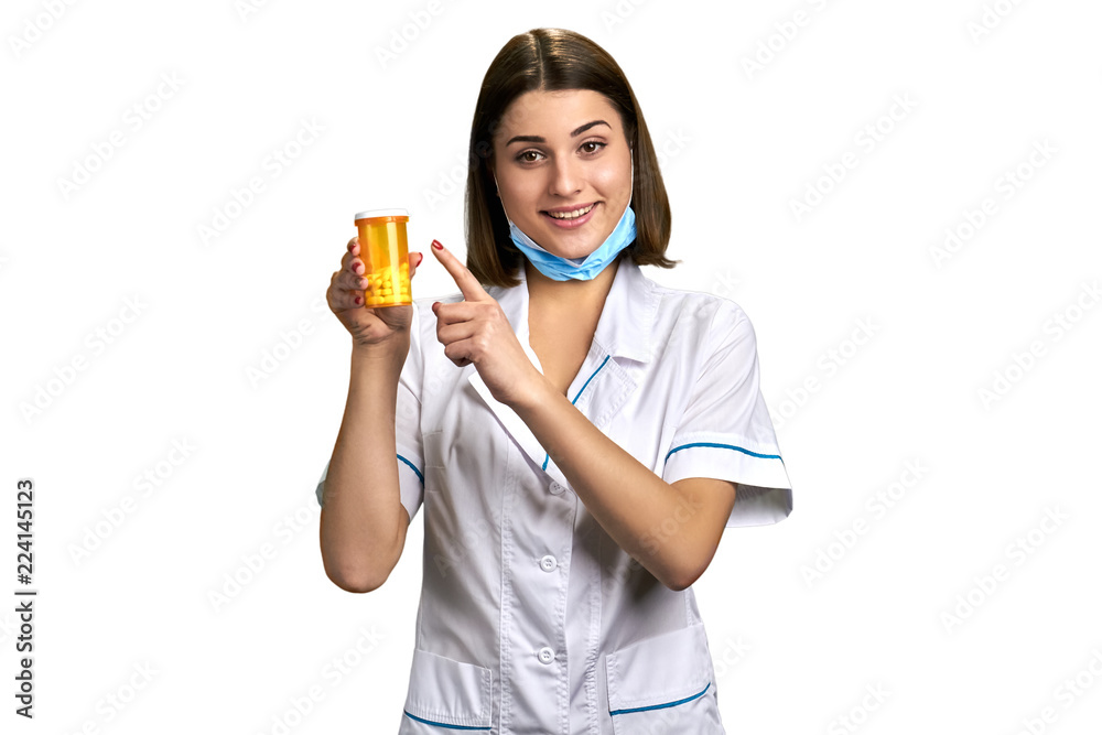 Smiling lady doctor pointing on pills. Portrait of young happy female doctor offering medication over white background. Smiling lady doctor pointing on pills. Portrait of young happy female doctor offering medication over white background.
