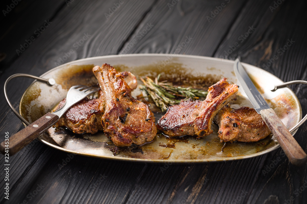 Lamb chops on a metal rustic plate with rosemary and spices Lamb chops on a metal rustic plate with rosemary and spices