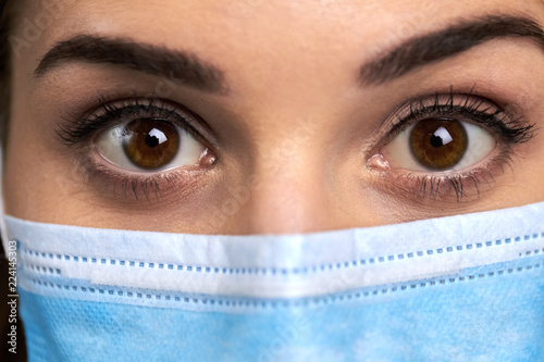 Close up widely opened eyes of doctor. Female doctor in protective mask with surprised eyes close up. Human expression of surprise. Hazel color eyes.