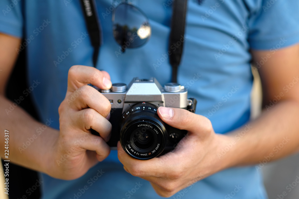 Close up, unrecognizable tourist man is holding an retro camera. Selective focus. Close up, unrecognizable tourist man is holding an retro camera. Selective focus.