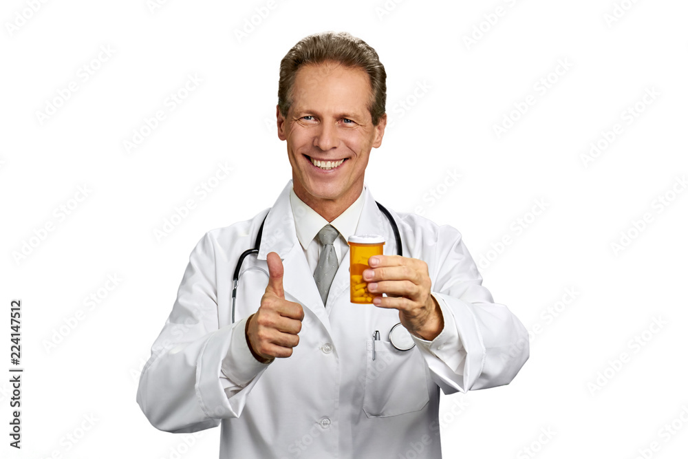Smiling practitioner showing thumb up gesture. Friendly smiling medic or doctor holding bottle of pills and giving okay sign, isolated on white background. Smiling practitioner showing thumb up gesture. Friendly smiling medic or doctor holding bottle of pills and giving okay sign, isolated on white background.