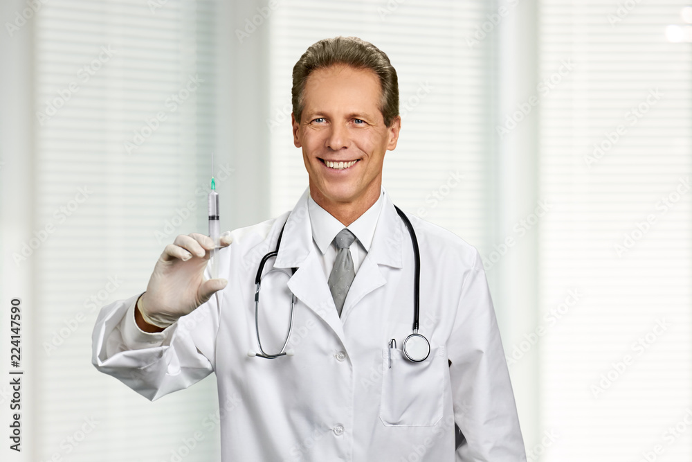 Portrait of happy doctor with syringe. Smiling medical specialist holding injection on blurred background. Vaccination and health care. Portrait of happy doctor with syringe. Smiling medical specialist holding injection on blurred background. Vaccination and health care.