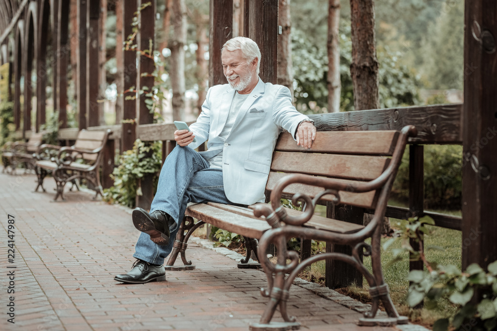 Waiting her. Cheerful stylish man expressing positivity while checking his email