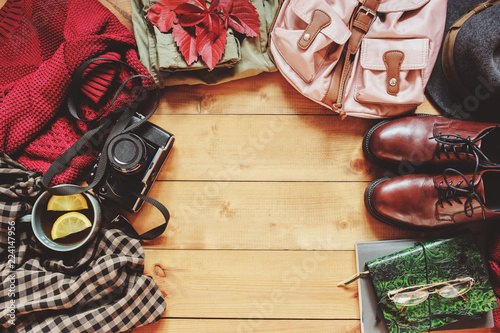 autumn women fashion clothes set with cozy sweater, shoes, plaid shirt, vintage photo camera, backpack and cup of tea. Fall seasonal walk concept, flat lay with empty space