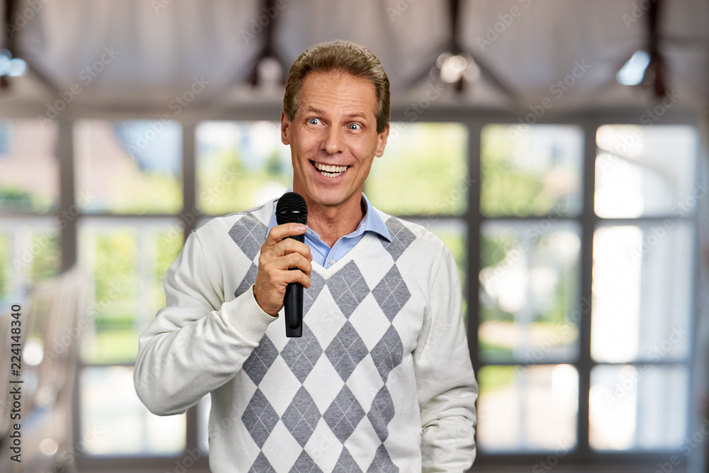 Happy smiling man holding microphone. Cheerful middle-aged man with  microphone on abstract window background. Television presenter at tv  programm. Stock-foto | Adobe Stock