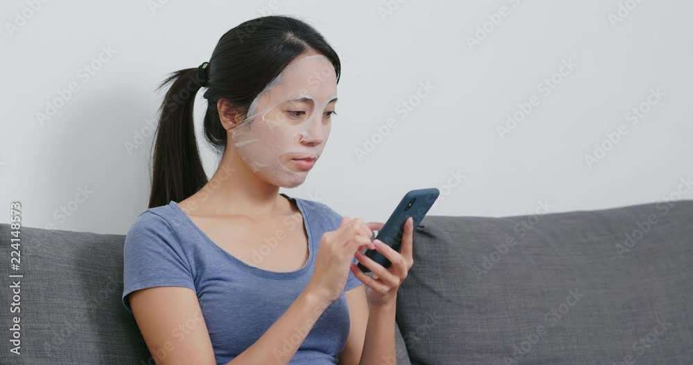 Woman apply paper mask on face and use of mobile phone Woman apply paper mask on face and use of mobile phone