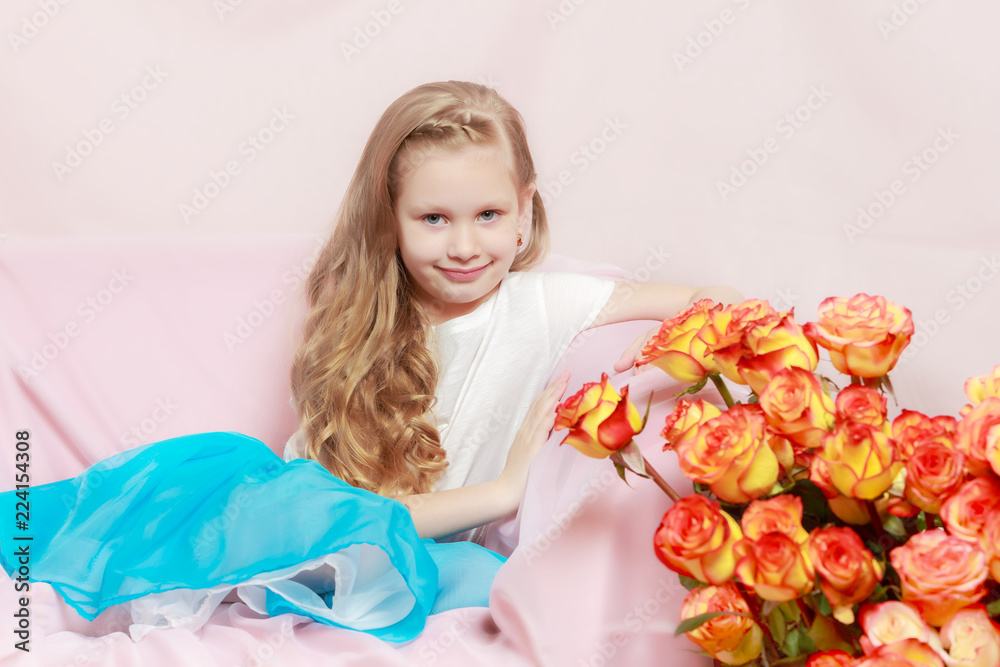 A beautiful little girl with long, light, curly hair, in a blue A beautiful little girl with long, light, curly hair, in a blue