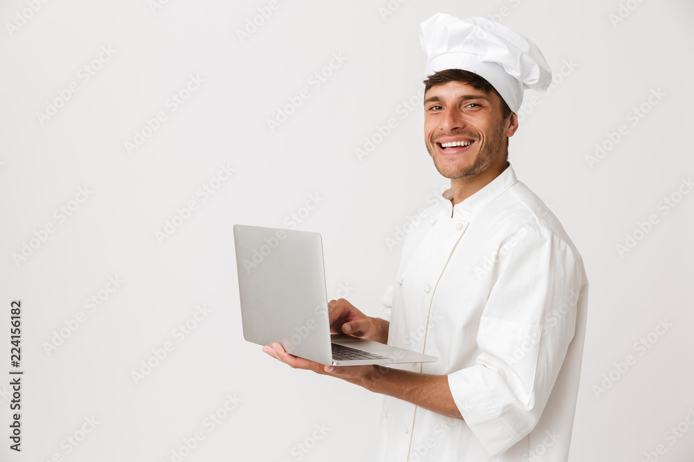 Chef man isolated over white wall background using laptop computer. Chef man isolated over white wall background using laptop computer.